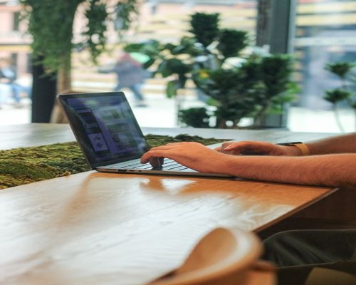 A professional typing on a clean notebook keyboard next to a window in an office workspace in Guadalajara